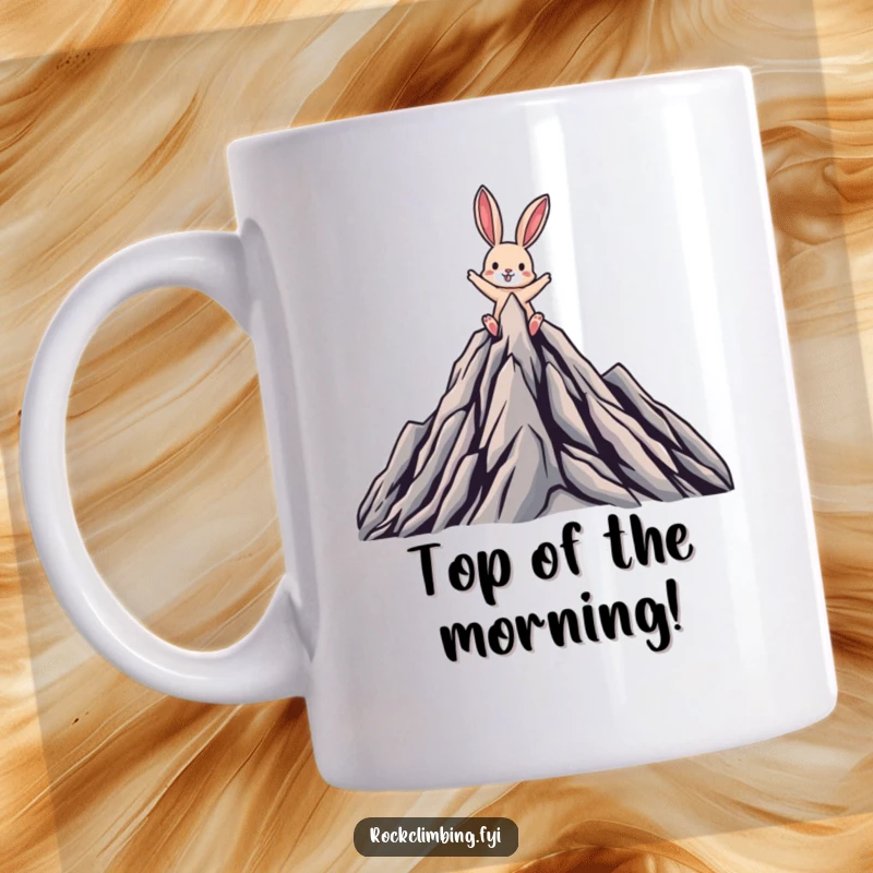 Funny mug shows a joyful rabbit triumphantly reaching the peak of a stylized, rugged mountain, celebrating ultimate success.