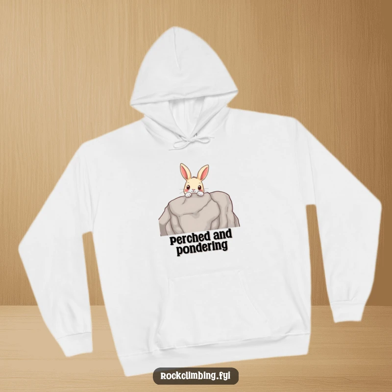 Funny hoodie showing a curious rabbit peeking over a rocky outcrop, offering warmth and a touch of woodland adventure.