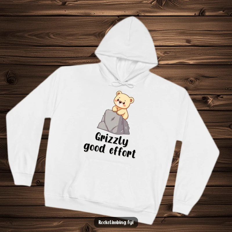 Funny hoodie featuring a determined bear cub scaling a small cliff with its little paws, offering warmth and motivational humor.